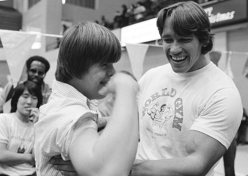 Arnold Schwarzenegger examine le biceps de John Riley après l'avoir aidé à faire 50 pompes dans une clinique des célébrités des Jeux olympiques spéciaux à Washington, DC, le 10 décembre 1978.