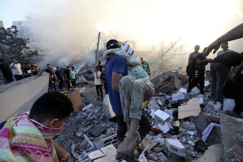Un Palestinien évacue une jeune fille blessée des lieux de destruction suite aux frappes aériennes israéliennes sur la ville de Gaza, le mercredi 25 octobre 2023.