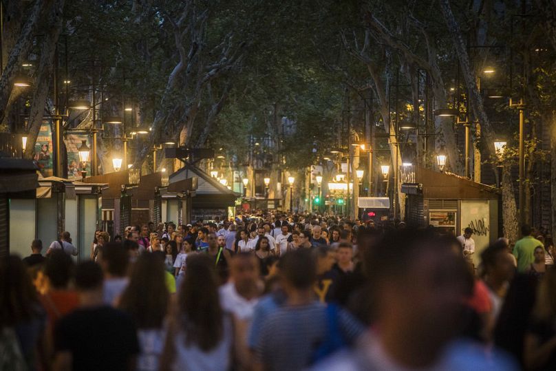 Des gens traversent la rue historique de Las Ramblas un jour après l'attaque terroriste, à Barcelone, en Espagne, le vendredi 18 août 2017.