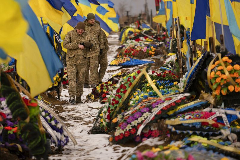 Des soldats ukrainiens marchent devant les tombes de leurs camarades à Kharkiv, en Ukraine, le jeudi 16 février 2023.