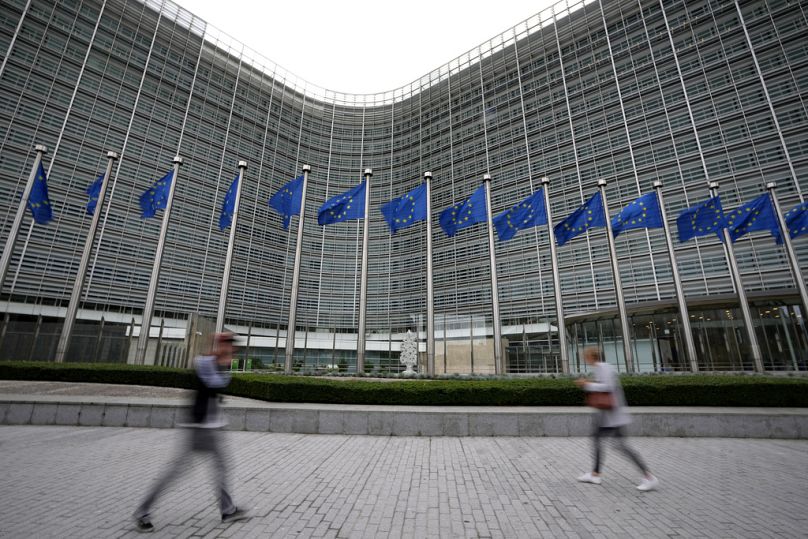 Les drapeaux de l’Union européenne battent au vent alors que les piétons passent devant le siège de l’UE à Bruxelles, en septembre 2023.