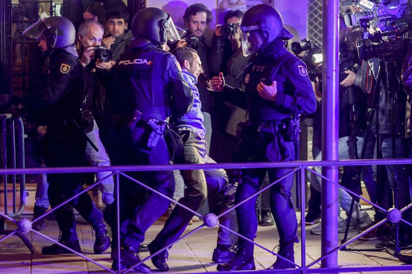 Un homme est arrêté par la police devant le siège du parti socialiste espagnol à Madrid, en Espagne.
