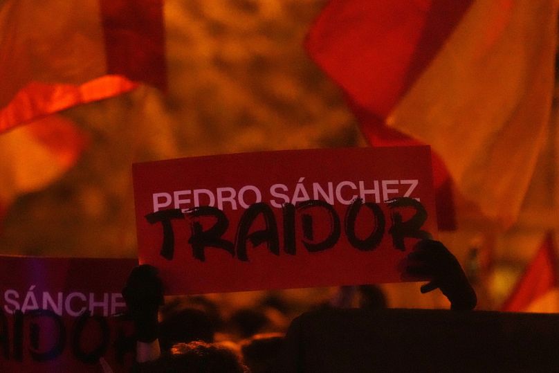 Un panneau indiquant « Pedro Sanchez, traître » est brandi lors d'une manifestation de manifestants de droite près du siège national du Parti socialiste espagnol à Madrid.