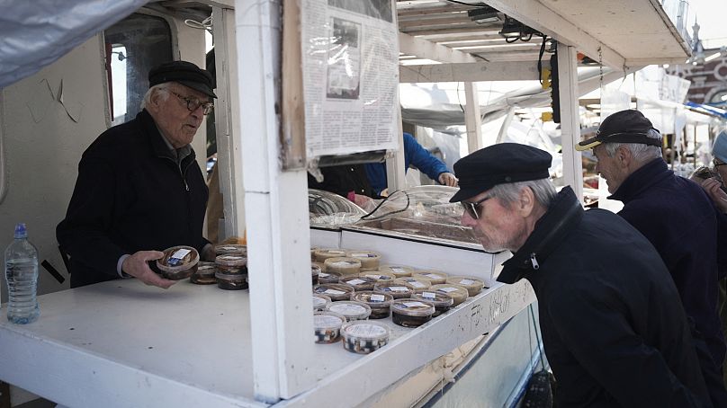 Le pêcheur de hareng Holger Sjogren (à gauche) vend des produits à base de hareng sur son bateau au marché aux poissons d'Helsinki, en Finlande, le 6 octobre 2023.