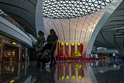 Des voyageurs passent devant le logo du Parti communiste décoré dans le hall des départs de l'aéroport international de Pékin Daxing, à Pékin, le 24 octobre 2023.