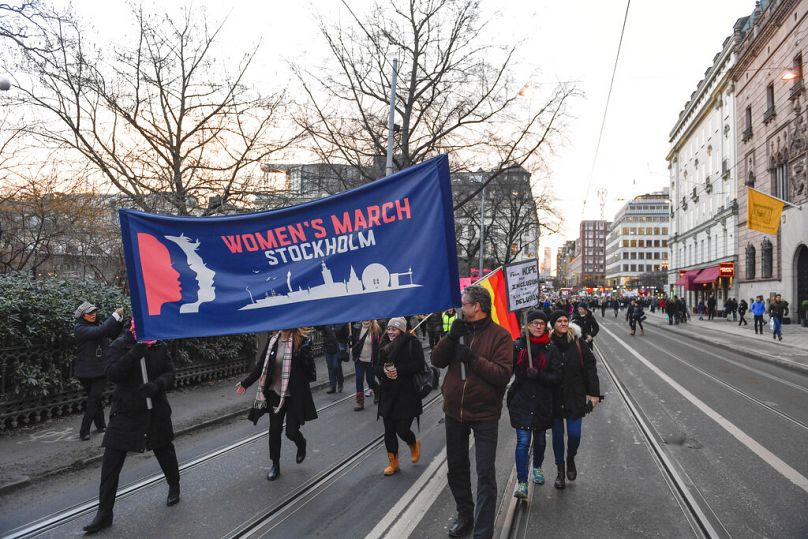 Des manifestants brandissant des banderoles et des pancartes participent à une marche des femmes à Stockholm, en Suède, le samedi 21 janvier 2017.