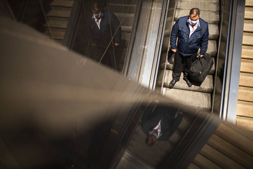 Un homme emprunte un escalier roulant pour entrer dans la gare et la station de métro Schuman à Bruxelles, juillet 2020