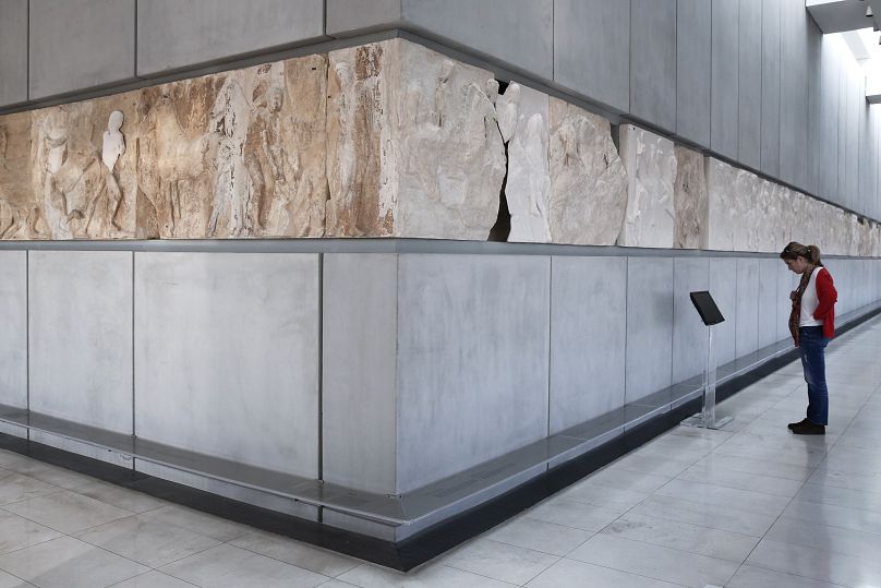 Un visiteur du musée de l'Acropole d'Athènes regarde la frise du temple du Parthénon, les parties blanches représentant les segments de la frise exposés au British Museum de Londres