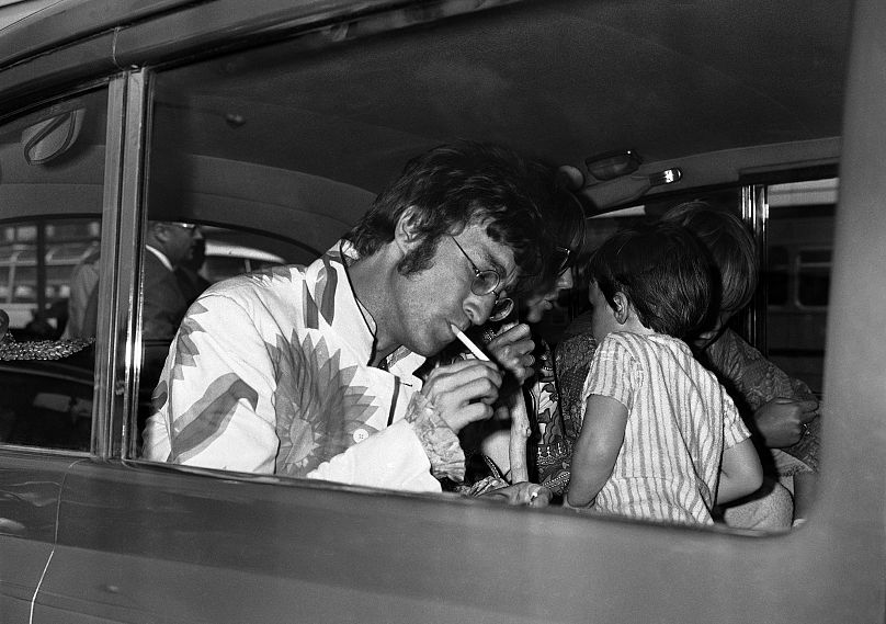 John Lennon des Beatles allume une cigarette à son arrivée à l'aéroport d'Heathrow à Londres, en Angleterre, depuis Athènes, en Grèce, le 31 juillet 1967.