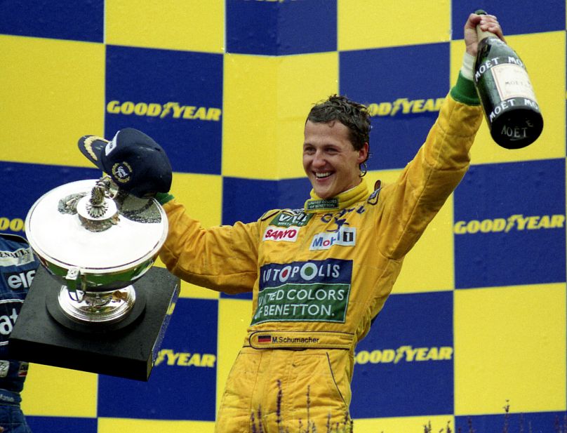 Michael Schumacher est tout sourire, tenant le trophée et la bouteille magnum de champagne, après avoir remporté son premier Grand Prix à Francorchamps, en Belgique, le 30 août 1992.