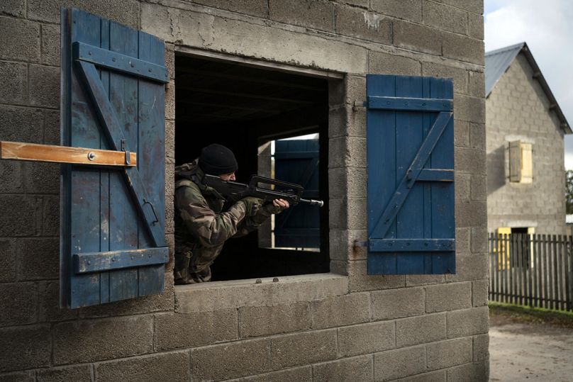 Un journaliste court avec des fantassins ukrainiens lors d'un entraînement avec des soldats français, en France, le mardi 7 novembre 2023.