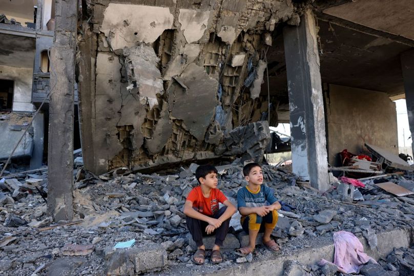 Des enfants sont assis au milieu des décombres d'un immeuble à la suite d'une frappe israélienne à Rafah, dans le sud de la bande de Gaza, vendredi.