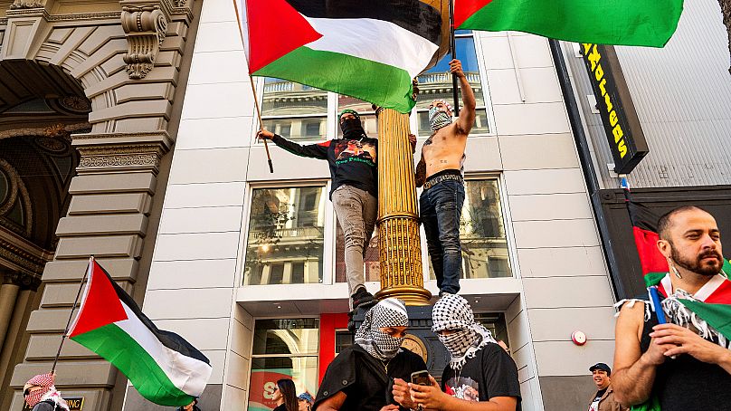 Des partisans pro-palestiniens grimpent sur une horloge lors d'une manifestation contre le sommet de l'APEC