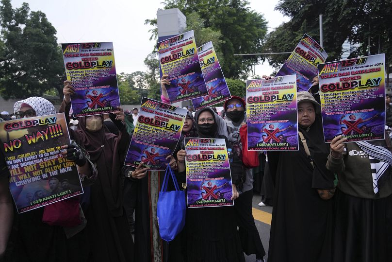 Des femmes musulmanes tiennent des affiches lors d'un rassemblement contre le groupe britannique Coldplay avant son concert à Jakarta, en Indonésie.