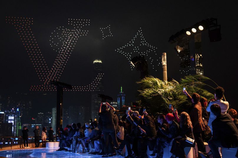 Un invité prend des photos d'un spectacle de drones lors du défilé de mode Louis Vuitton pour hommes pré-automne 2024 présenté à Hong Kong, le jeudi 30 novembre 2023.