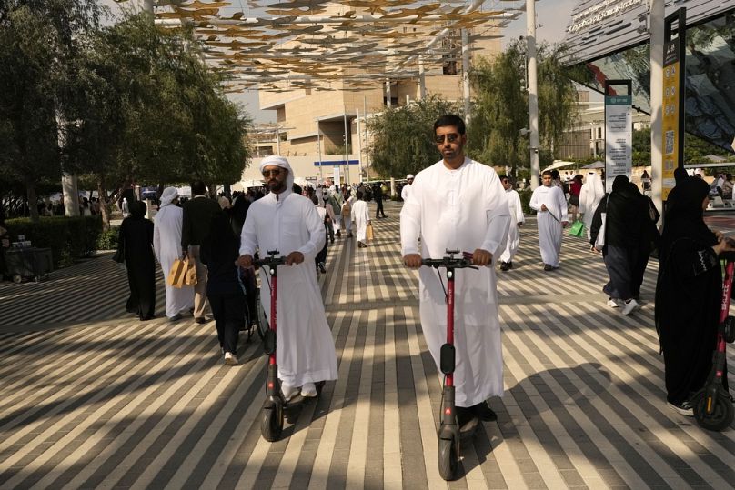 Des gens conduisent un scooter électrique lors du Sommet des Nations Unies sur le climat COP28, décembre 2023