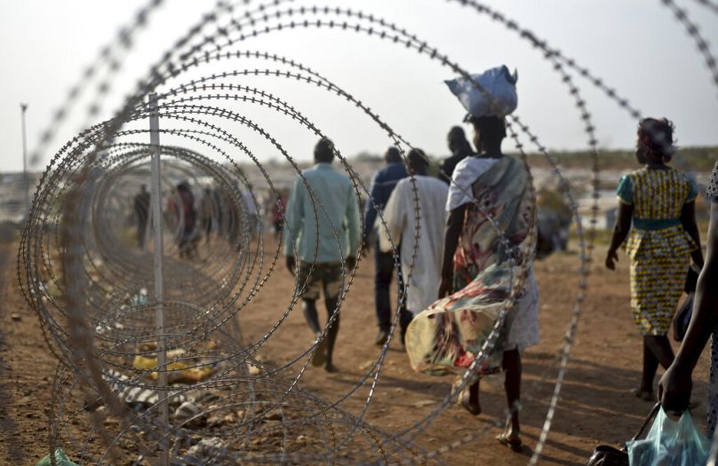 Des personnes déplacées marchent à côté d'une clôture en barbelés barbelés sur la base des Nations Unies à Juba, la capitale, au Soudan du Sud, en janvier 2016.
