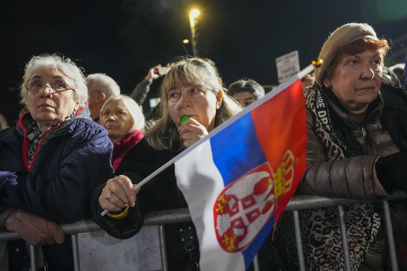 Une femme brandit un drapeau serbe lors d’un dernier rassemblement préélectoral de l’opposition