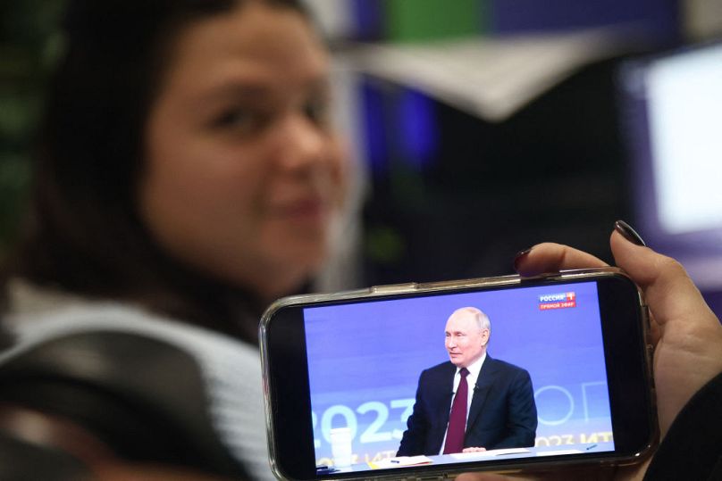 Une femme regarde la conférence de presse de fin d'année du président russe Vladimir Poutine retransmise en direct sur un smartphone dans un bureau de Simferopol, en Crimée.