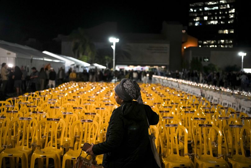 Une femme passe devant des chaises vides attachées ensemble dans une installation artistique représentant des otages détenus par le Hamas sur la place des otages du Musée d'art de Tel Aviv, novembre 2023.
