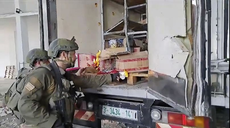 Cette image réalisée à partir d'une vidéo non datée partagée sur X montre des soldats de l'armée israélienne essayant de brûler des réserves de nourriture et d'eau à l'arrière d'un camion abandonné à Gaza.