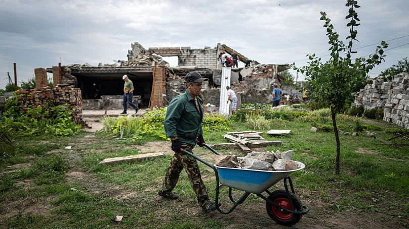 Un volontaire transporte des charrettes remplies d'ordures lors du nettoyage de la maison de Zhanna et Serhiy Dynaeva, détruite par les bombardements russes, près de Tchernihiv.