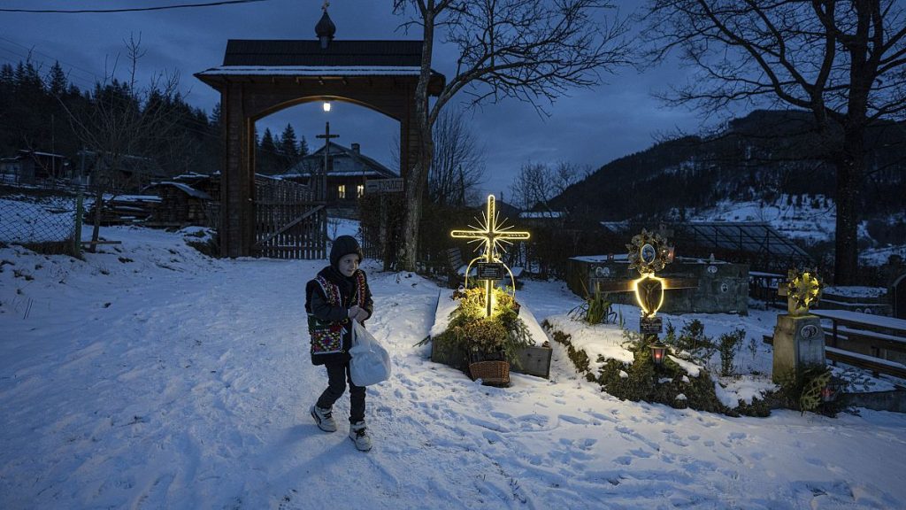 A boy walks at the cemetery after church Christmas service in Kryvorivnia village, Ukraine, on 24 Dec 2023