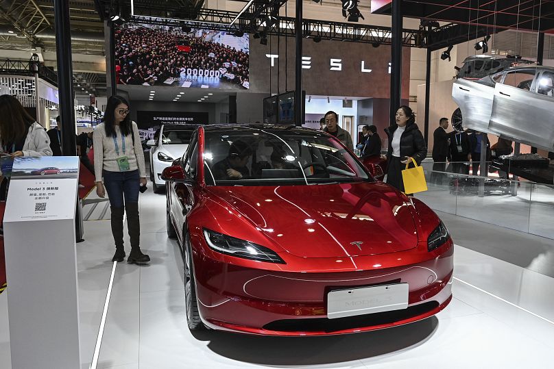 Des gens essayent le véhicule électrique Model 3 de Tesla sur son stand lors du China International Supply Chain Expo (CISCE) à Pékin, le 1er décembre 2023. JADE GAO / AFP