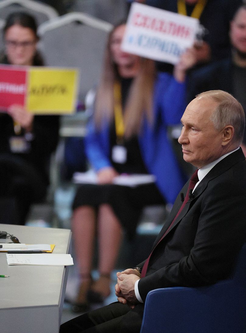 Les journalistes brandissent des pancartes pour attirer l'attention du président russe Vladimir Poutine lors de sa conférence de presse de fin d'année