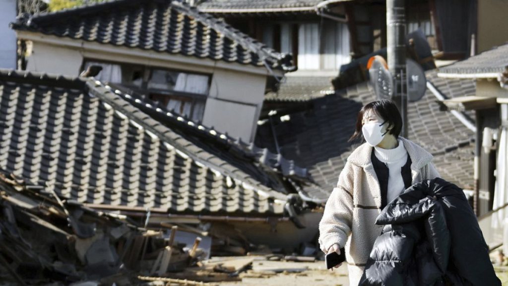 A woman walks in front of collapsed houses following earthquake in Noto-cho, Ishikawa prefecture, Japan