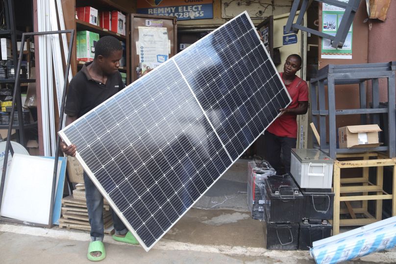 Des hommes exposent un panneau solaire à vendre dans un magasin à Abuja, juin 2023