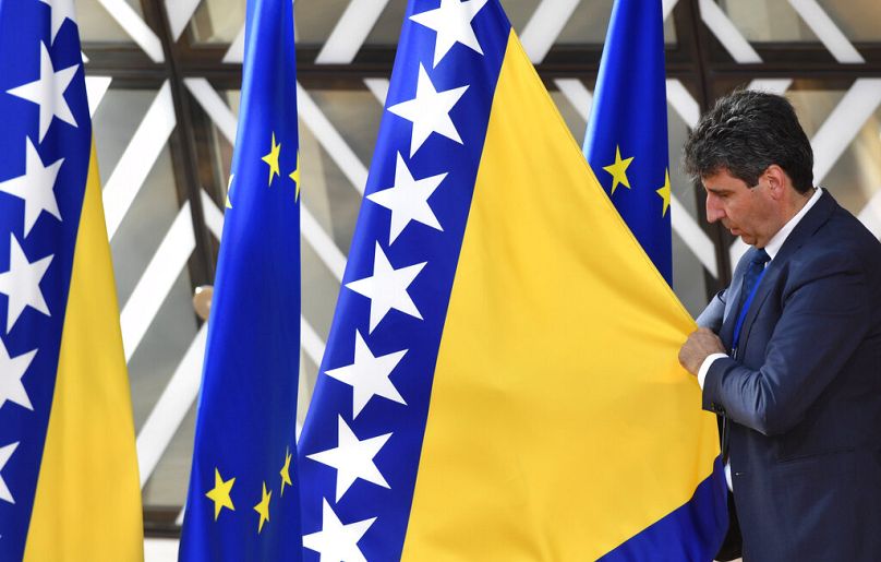 Un membre du protocole ajuste le drapeau de la Bosnie-Herzégovine avant son arrivée à un sommet de l'UE à Bruxelles, juin 2022