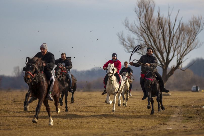 Des gens participent à une course de chevaux lors des célébrations de l'Épiphanie dans le village de Pietrosani, en Roumanie, le samedi 6 janvier 2024.