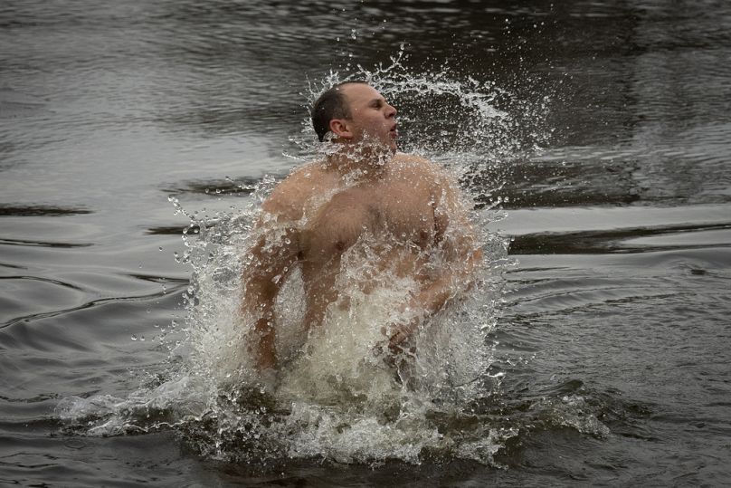 Un homme fait des gestes dans l'eau glacée du Dnipro, lors d'une célébration traditionnelle de l'Épiphanie à Kiev, en Ukraine, le samedi 6 janvier 2024.