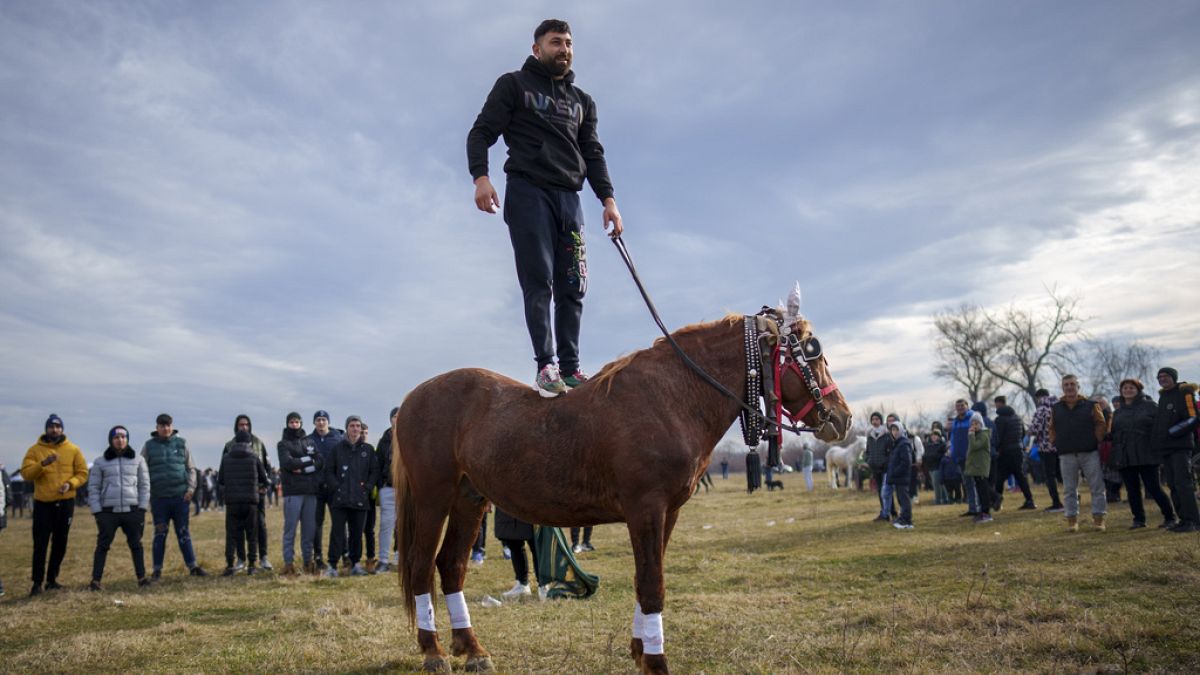 A man stands on a horse during Epiphany celebrations in the village of Pietrosani, Romania, Saturday, Jan. 6, 2024.