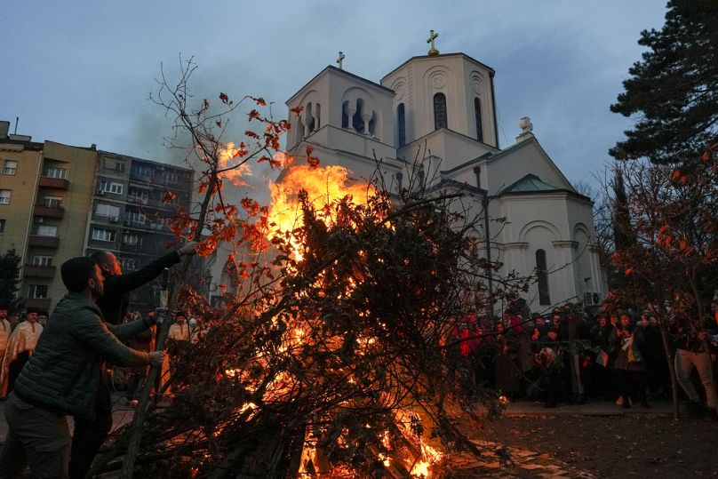 Des gens brûlent des branches de chêne séchées, le symbole de la bûche de Noël pour la veille de Noël orthodoxe, devant l'église Saint-Sava à Belgrade, en Serbie.