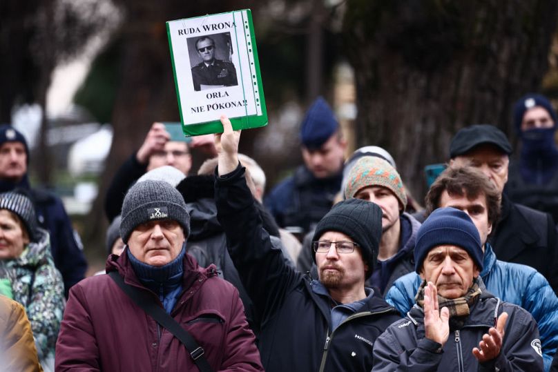 Un homme tient une banderole avec Tusk habillé en chef d'État de l'ère communiste, le général Wojciech Jaruzelski lors d'une manifestation contre les changements dans les médias publics à Cracovie