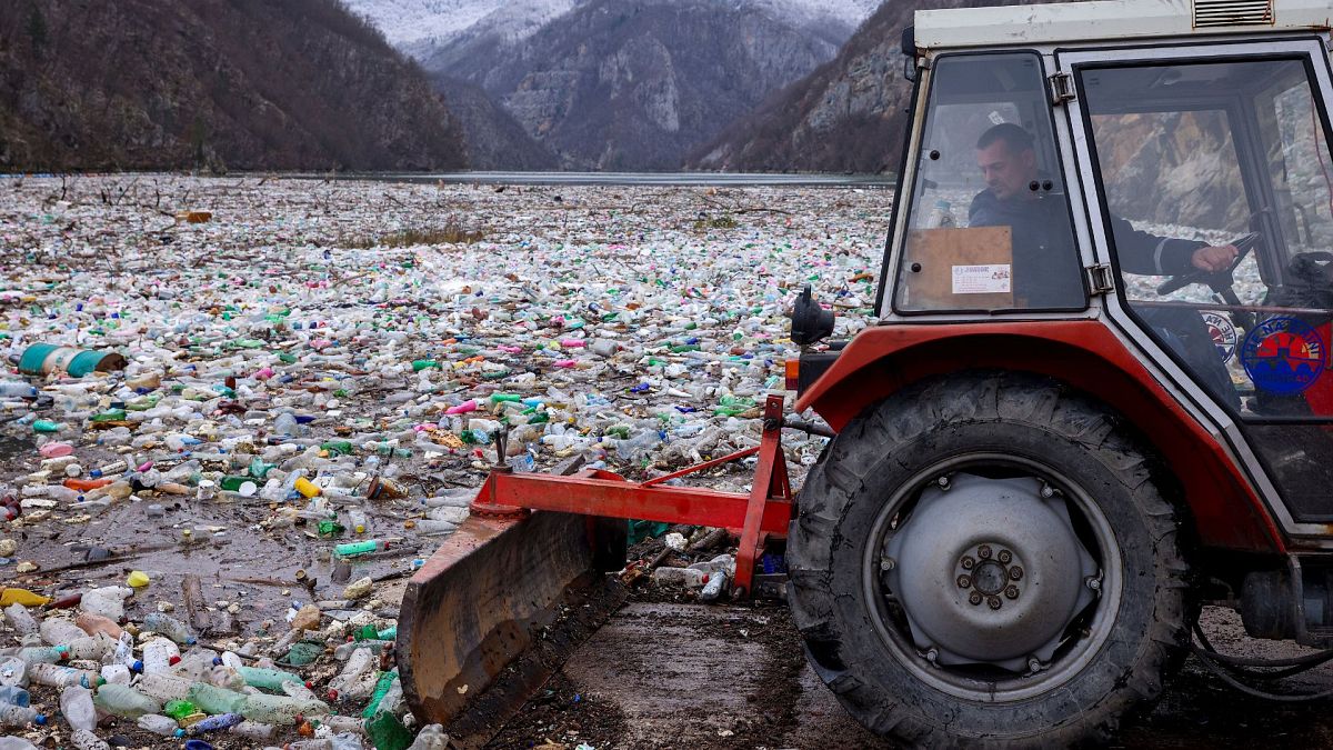 A worker uses a tractor to push the waste back in the Drina river near Visegrad, Bosnia, 10 January 2024.