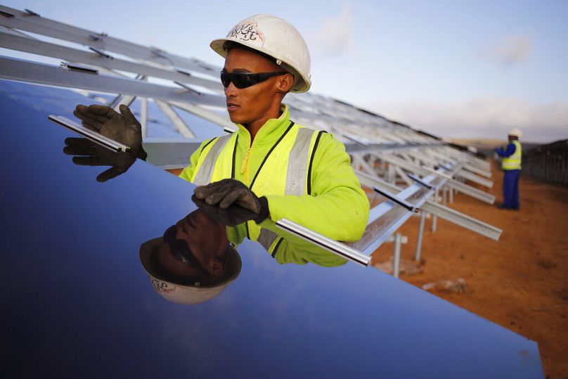 Un ouvrier installe un panneau solaire dans un parc solaire photovoltaïque situé à la périphérie de la ville côtière de Lamberts Bay, Afrique du Sud, mars 2016.
