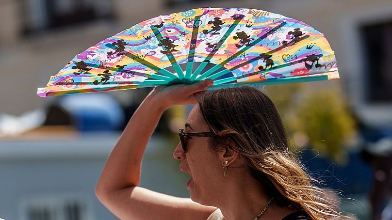 Une femme se protège du soleil avec un éventail à main à Madrid, Espagne, le 10 juillet 2023.