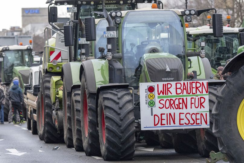 Un panneau en allemand disant "Nous, les agriculteurs, prenons soin de votre alimentation" est accroché à un tracteur garé le long de la Bismarckstraße lors de la manifestation des agriculteurs à Berlin, le 15 janvier 2024.