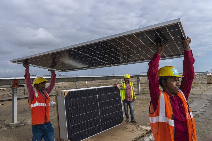 Les travailleurs transportent un panneau solaire à installer dans le parc énergétique en construction dans le désert de sel près de Khavda, État du Gujarat, Inde, septembre 2023