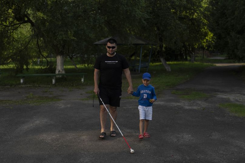 Denys Abdulin, un ancien soldat ukrainien aveuglé pendant la guerre, se promène avec son fils Vadym, près de Rivne, juillet 2023