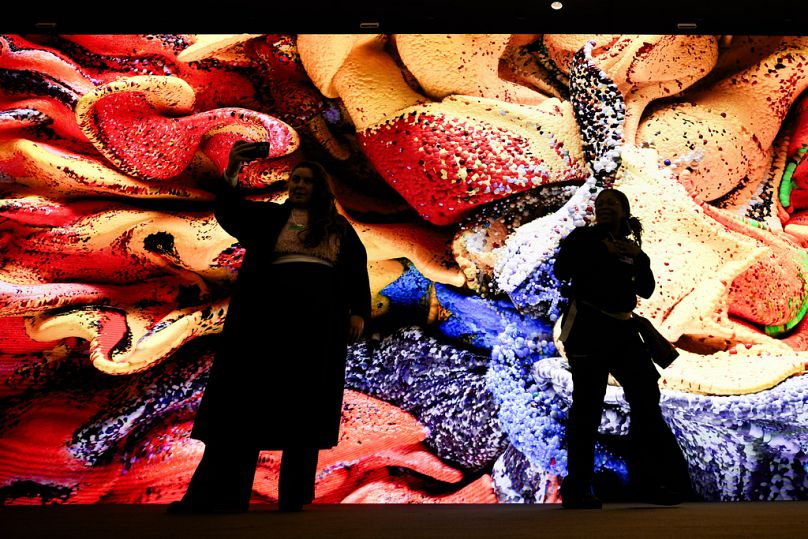 Des gens se rassemblent devant un écran avec une œuvre d'art générée par l'intelligence artificielle par l'artiste médiatique Refik Anadol à Davos, janvier 2024.