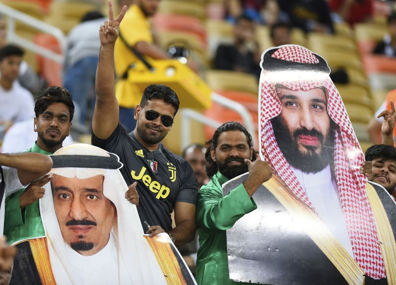 DOSSIER – Des fans saoudiens tiennent des photos du roi Salmane d'Arabie saoudite, à gauche, et du prince héritier saoudien Mohammed ben Salmane.