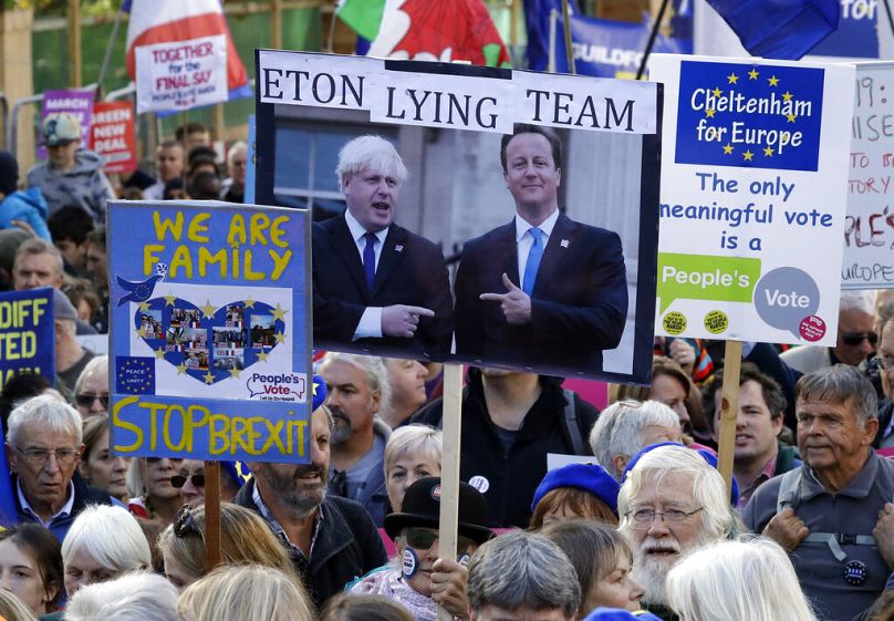Des partisans de l'UE tiennent une pancarte montrant les anciens Premiers ministres Boris Johnson et David Cameron alors qu'ils participent à une marche de protestation pour le vote du peuple à Londres, 2019.