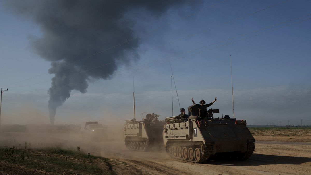 Israeli soldiers move on armored personnel carriers (APC) near the Israeli-Gaza border as smoke rises to the sky in the Gaza Strip, 21/1/2024.