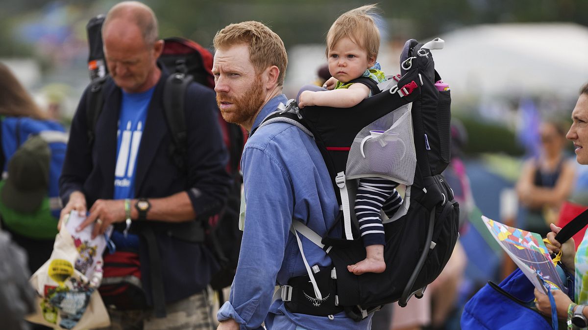 An adult carrying a child at Glastonbury Festival in Somerset, England. June 23, 2022.