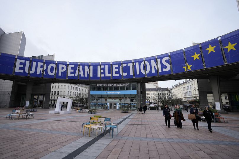 Des gens marchent sous une banderole annonçant les élections européennes devant le Parlement européen à Bruxelles, janvier 2024.