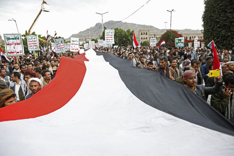 Les partisans des Houthis scandent des slogans en tenant des pancartes lisant 